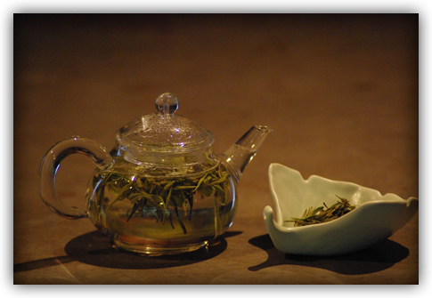 tea steeping in glass pot with ginkgo leaf-shaped ceramic dish of dry leaf